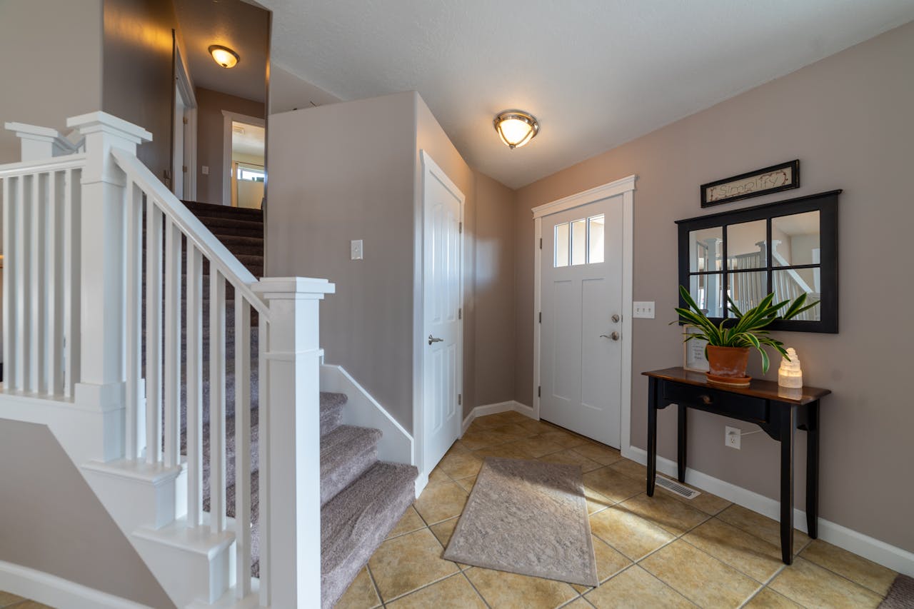 Bright entryway featuring stairs, a door, and stylish interior design elements.