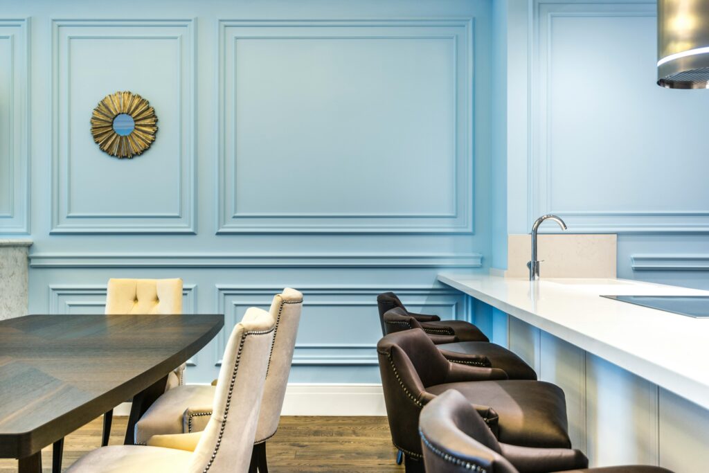 Stylish dining room featuring modern furniture, soft blue walls, and a sleek countertop.
